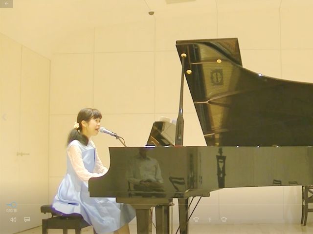 出張歌手として、舞台で演奏する様子。ピアノ弾き語りの姿。